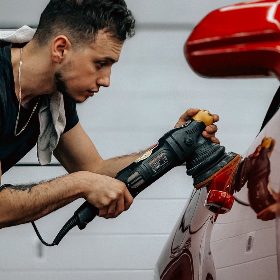 Detailer machine-polishing a red car's paint