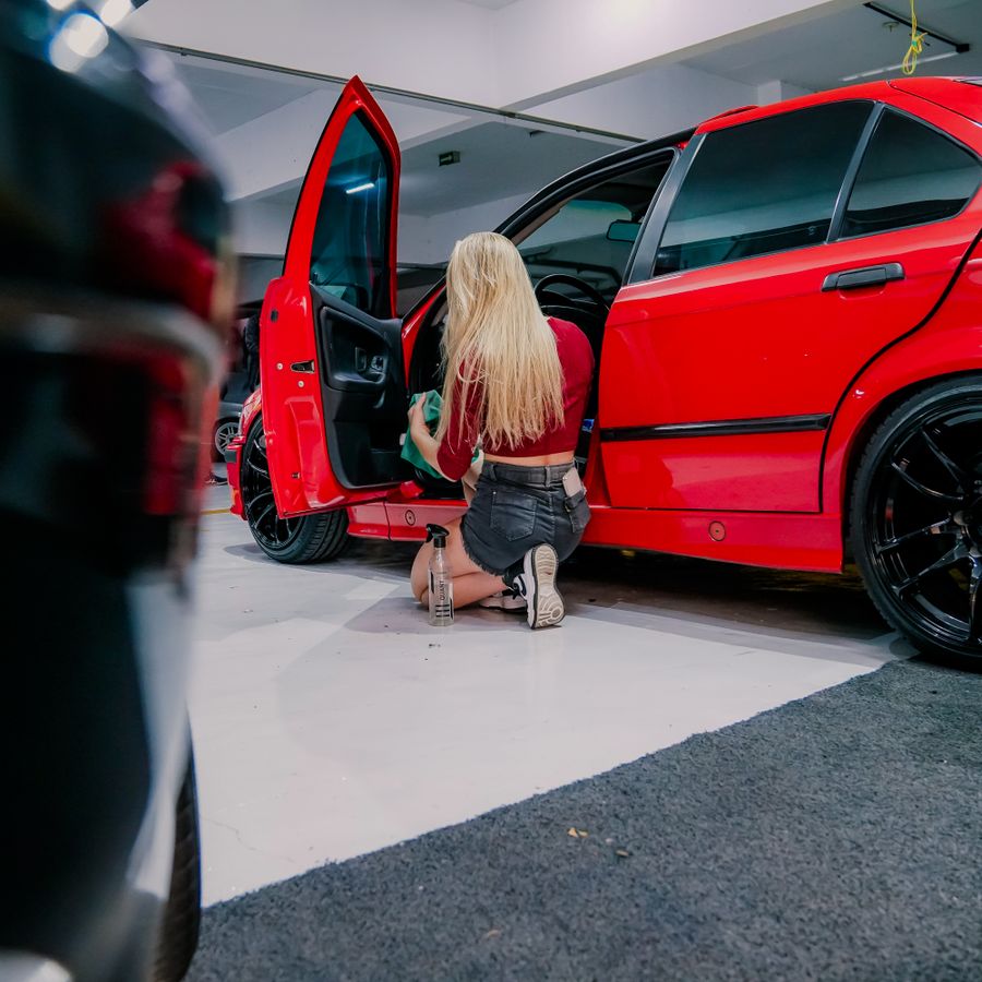 Detailer cleaning the interior of a red sedan