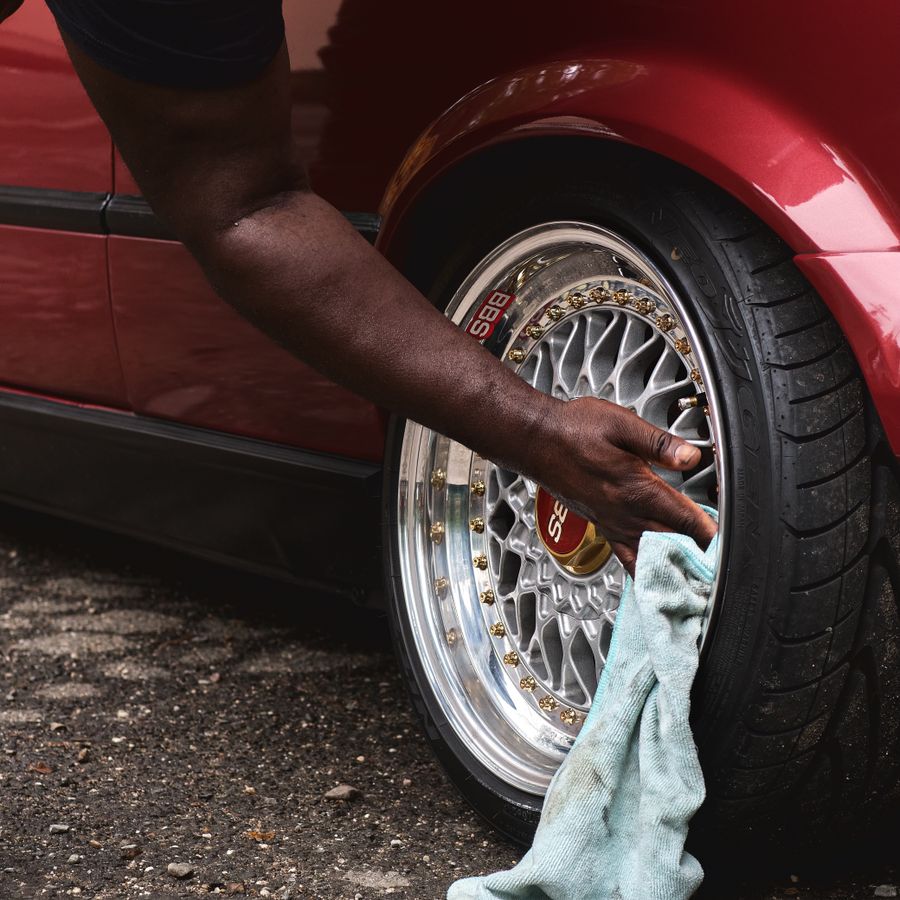 Hands cleaning an alloy wheel with a cloth